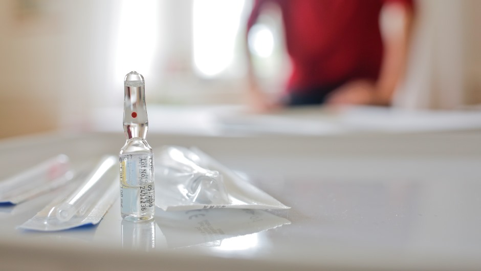 Fokus auf Medikament in flüssiger Ausführung daneben sind Verpackungen erkenntlich, die aber nicht zu zuordnen sind.